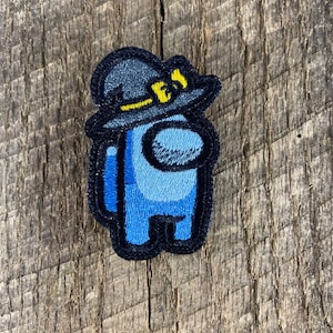 Puede incluir: Parche azul bordado de un personaje de Among Us con un sombrero de bruja negro con un borde amarillo.