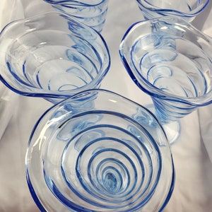 May include: Five blue glass cups with a swirling design. The cups are clear and have a textured surface.