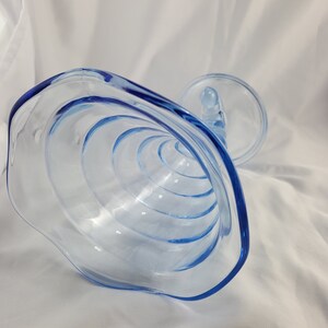 May include: A clear blue glass bowl with a scalloped edge and a spiral design. The bowl is upside down, showing the interior.