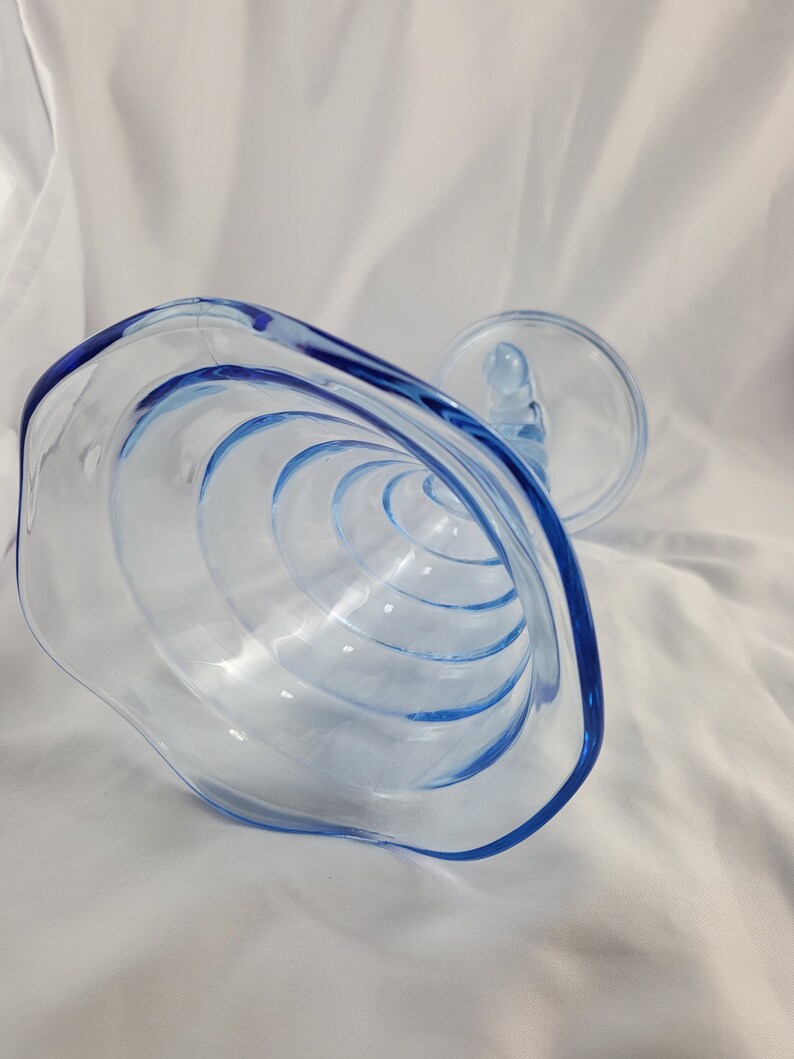 May include: A clear blue glass bowl with a scalloped edge and a spiral design. The bowl is upside down, showing the interior.
