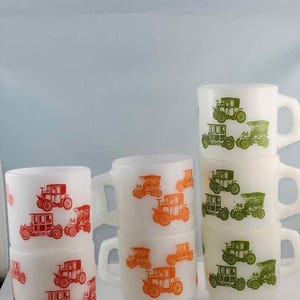 May include: Set of six vintage milk glass mugs with a repeating pattern of antique cars in green, orange, and red. The mugs are stacked in three groups of two.