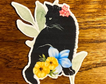 May include: A black cat sticker with a floral design. The cat is adorned with pink flowers on its head and surrounded by yellow and blue flowers. Green leaves are also present in the design.