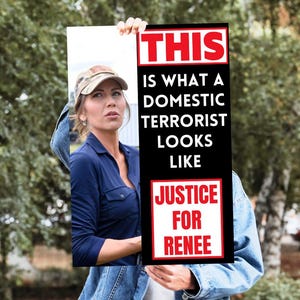 May include: A sign with the text "THIS IS WHAT A DOMESTIC TERRORIST LOOKS LIKE" in white letters on a black background. The sign also says "JUSTICE FOR RENEE" in red letters. A person is holding the sign.