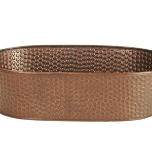 May include: Oval-shaped, hammered copper-colored metal tub with two curved handles. The tub has a textured surface with a pattern of small, evenly spaced dimples. The container is empty and sits against a white background.
