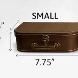May include: A small brown rectangular suitcase with a top handle and a metal latch. The suitcase features white stitching along the edges. Dimensions are labeled as 5.5 inches in depth, 3 inches in height, and 7.75 inches in width.