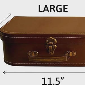 May include: A large brown rectangular suitcase with white stitching along the edges. The suitcase features a metallic latch and a handle on the front. The text LARGE is printed above the suitcase, and 11.5 inches is printed below it.