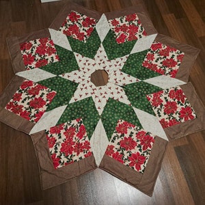 Könnte beinhalten: Ein brauner, grüner, weißer und roter gesteppter Christbaumrock mit einem Sternmuster. Der Rock ist aus Stoff mit einem Blumenmuster.