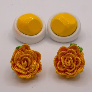 May include: A pair of yellow flower earrings with white and yellow button earrings.
