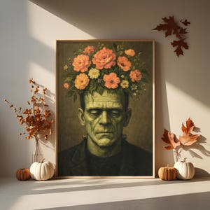 May include: A framed print depicting Frankenstein's monster adorned with a crown of orange and yellow roses. The artwork has a vintage style, with a muted colour palette and a gold frame. Pumpkins and autumn leaves are in the foreground.