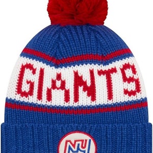 May include: Blue knitted beanie with a white pom pom and a white "Giants" logo with red accents. The beanie also features a blue and white circular patch with the letters "NY" in white.