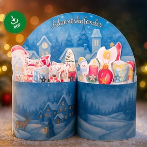 Könnte beinhalten: Blauer Adventskalender mit einer Winterdorf-Szene. Der Kalender zeigt Miniaturhäuser, schneebedeckte Bäume und festliche Figuren. Auf der Oberseite des Kalenders steht "Adventskalender". Der Kalender ist mit kleinen Geschenken und Dekorationen gefüllt.