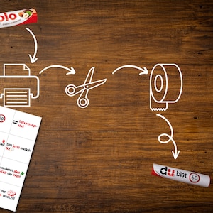 May include: A set of printable cards with the text "bist 60" and other German phrases. The cards are shown next to a printer, scissors, tape, and a tube of glue.