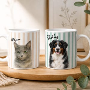 Könnte beinhalten: Zwei weiße Keramikbecher mit Tierporträts. Auf einem Becher ist eine graue Katze namens Mina abgebildet, auf dem anderen ein Hund namens Shelby. Beide Becher haben vertikal gestreifte Hintergründe in Pastellfarben.