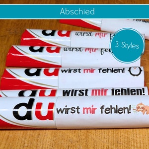 Könnte beinhalten: Ein Set aus vier roten und weißen Schokoladentafeln mit weißen Etiketten, auf denen in schwarzer Schrift "du wirst mir fehlen!" steht. Die Etiketten zeigen außerdem einen Pinguin, ein Faultier und den Text "3 Styles".