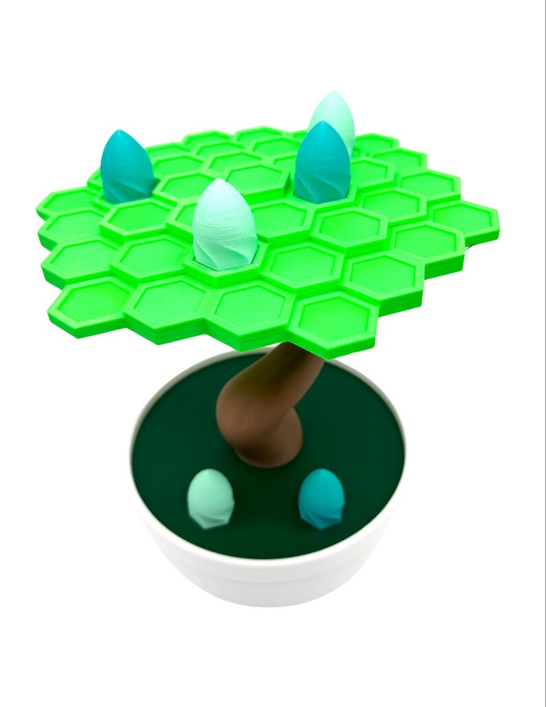 May include: A whimsical, 3D-printed tree sculpture. The tree features a bright green, hexagonal canopy with teal and light green bud-like structures. The brown trunk rises from a dark green base within a white bowl. Additional teal buds are at the base.