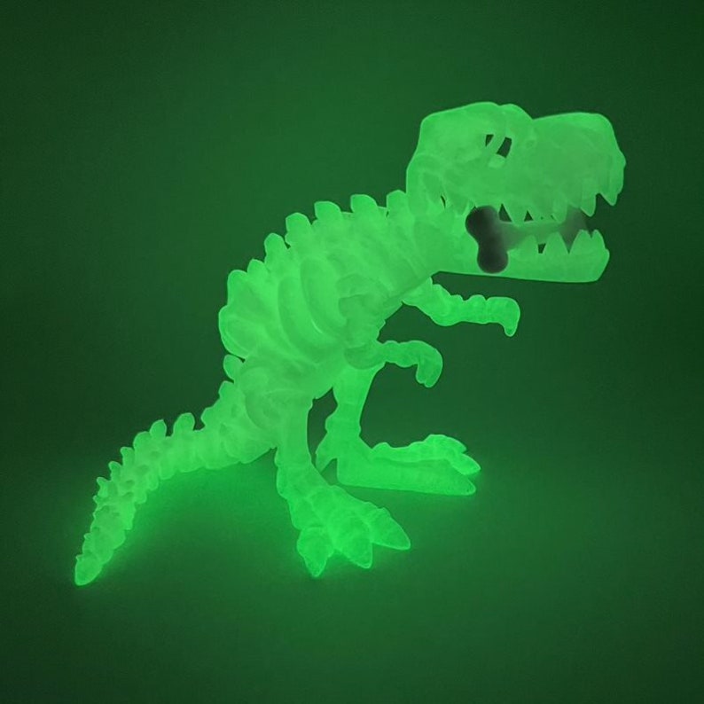 May include: A green glow-in-the-dark dinosaur skeleton toy. The dinosaur is posed in a standing position with its mouth open and a bone in its mouth.