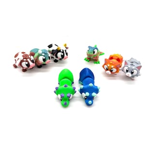 May include: A set of nine small, colourful figurines, including a cow, a cat, a dinosaur, and a lizard. The figurines are made of plastic and have a cartoonish style.