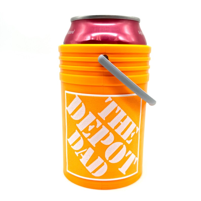 May include: Orange can cooler with a gray handle. The cooler has the words "The Depot Dad" printed on it.
