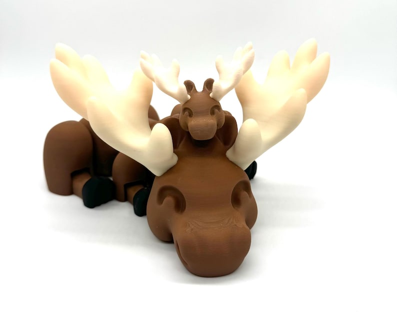 Op de afbeelding: Een bruine elandfiguur met een kleinere bruine elandfiguur erop. Beide elanden hebben witte geweien.