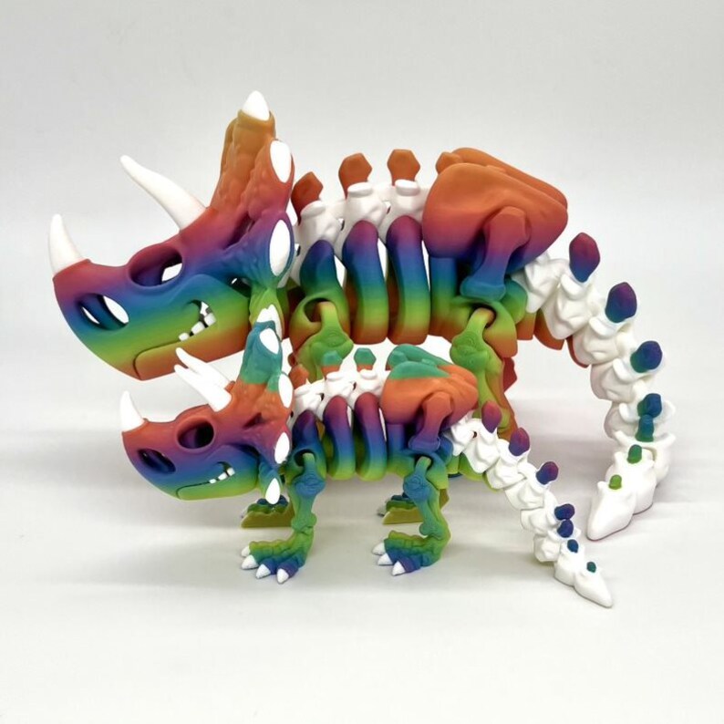 May include: A rainbow colored 3D printed skeleton of a triceratops and a smaller dinosaur. The skeletons are articulated and poseable.