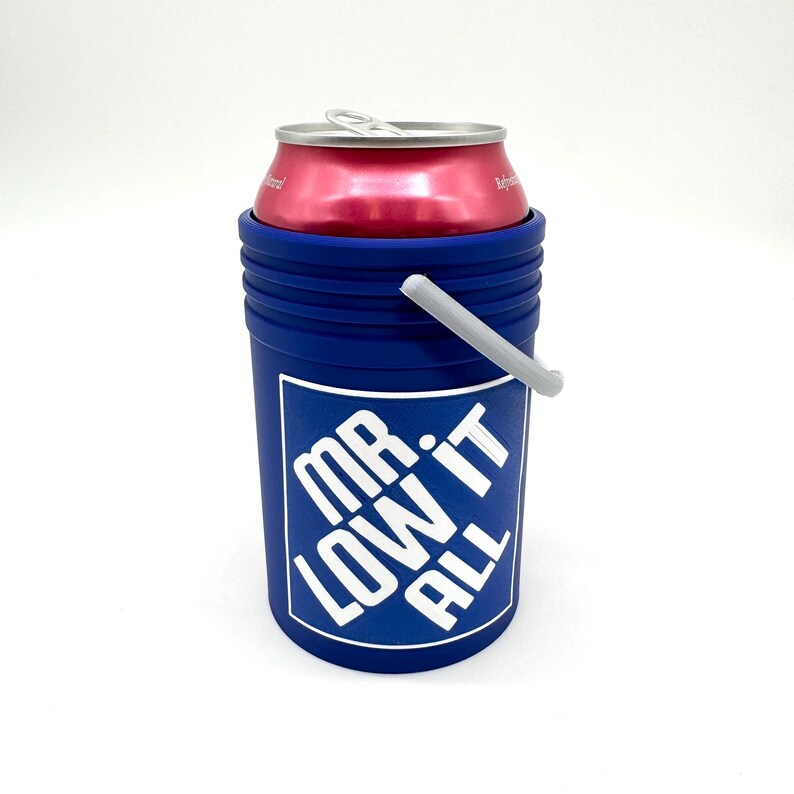 Puede incluir: Un enfriador de latas azul con un gr&aacute;fico blanco que dice "MR. LOW IT ALL". Una lata roja est&aacute; dentro del enfriador. El enfriador tiene un asa gris y est&aacute; sobre un fondo blanco.