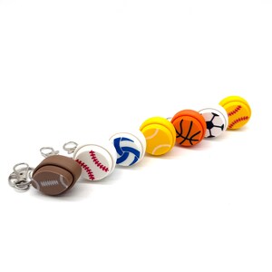 May include: A set of seven keychains featuring different sports balls. The keychains are made of plastic and feature a variety of colors, including red, white, blue, yellow, orange, and black. The keychains are arranged in a row, with the football keychain on the left and the baseball keychain on the right.