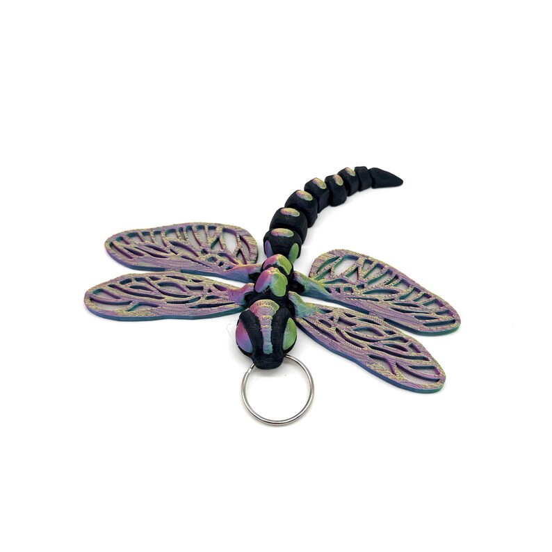 May include: A black and iridescent dragonfly keyring with a silver ring. The dragonfly has a detailed, intricate design on its wings.