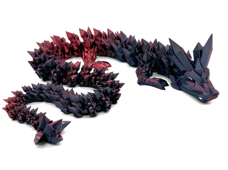 May include: A black and red crystal dragon figurine with a long, curled tail. The dragon is made of a shiny, textured material and has a detailed design.
