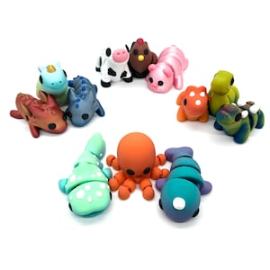 May include: A collection of ten colourful handmade polymer clay animal figurines. The figurines include a red dragon, a blue and grey seahorse, a green and white spotted fish, a purple and blue segmented fish, a red octopus, a green frog, a brown and white cow, a pink pig, a brown chicken, and a green and brown lizard.