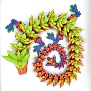 May include: A colorful 3D printed dragon made of plastic with a green, yellow, orange, red, purple, and blue color scheme. The dragon is curled up in a spiral shape.