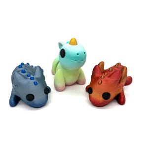 May include: Three small, hand-painted figurines: a blue and grey dragon, a green and blue unicorn, and a red and orange dragon.