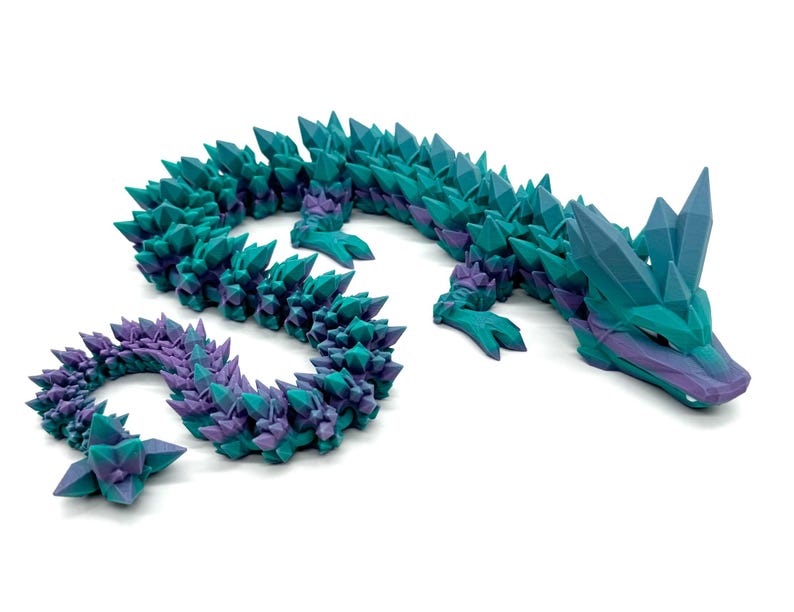 May include: A teal and purple crystal dragon figurine with a spiky, textured body. The dragon is posed with its head raised and its tail curled.