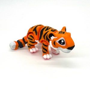 K&ouml;nnte beinhalten: Ein kleines orangefarbenes und schwarzes Tiger-Spielzeug mit wei&szlig;en Akzenten. Das Spielzeug ist aus Kunststoff und hat einen segmentierten K&ouml;rper. Der Tiger hat gro&szlig;e, schwarze Augen und einen freundlichen Ausdruck.