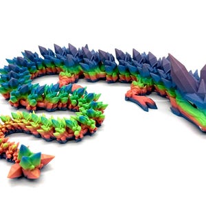 May include: A rainbow-colored dragon figurine with a crystal-like texture. The dragon is curled up in a serpentine shape with its head raised.