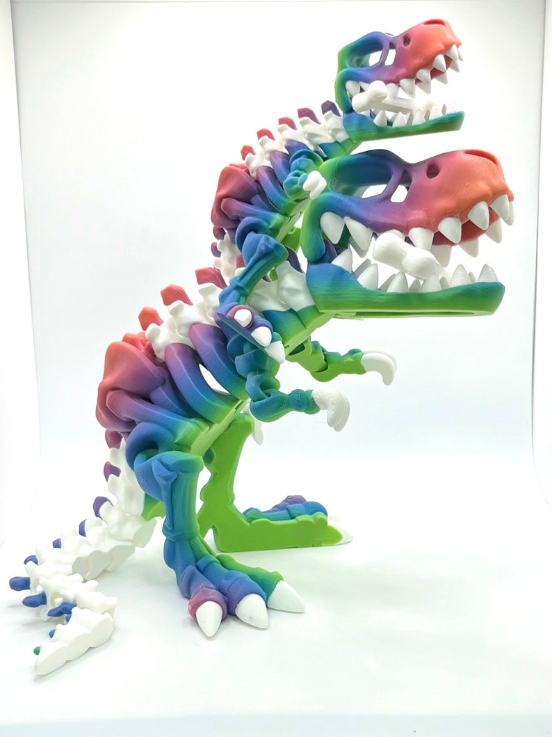May include: A multi-colored 3D printed dinosaur skeleton with a rainbow color scheme. The dinosaur has three heads and is standing on a white surface.