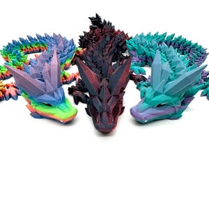 May include: Three 3D printed dragon figurines, each with a different color scheme. The first dragon is a vibrant purple and green, the second is a dark red and black, and the third is a teal and purple.
