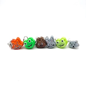 May include: A set of six colorful plastic animal-shaped stitch markers. The markers feature a fox, frog, hedgehog, bunny, frog, and wolf.