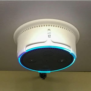 May include: A white smart home device with a black speaker and a blue light ring. The device is mounted on a ceiling and has the word "Cia" printed on it.