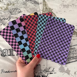 May include: Five checkerboard patterned cards with glitter accents. The cards are in shades of purple, blue, red, and yellow.