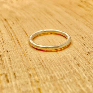 May include: A simple silver band ring with a hammered texture.