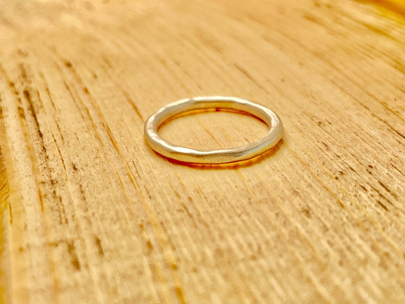 May include: A simple silver band ring with a hammered texture.