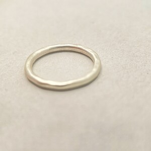 May include: A simple silver band ring with a hammered finish.