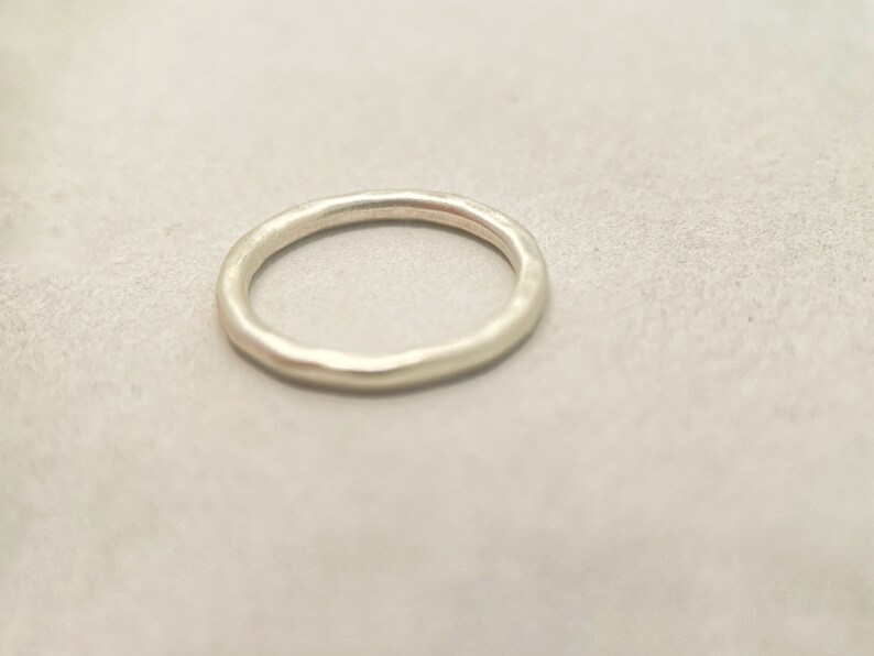 May include: A simple silver band ring with a hammered finish.