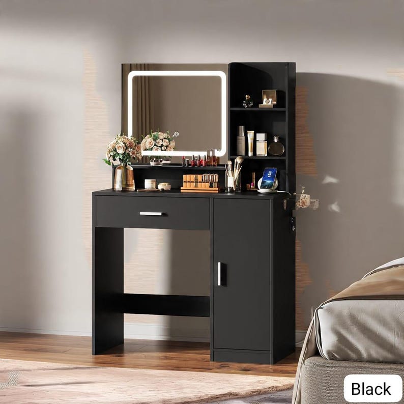 May include: Black vanity with a lighted mirror, drawer, and cabinet. The vanity has a built-in shelf for storage and a space for a chair. The mirror is surrounded by a bright white light. The vanity is designed for makeup and beauty products.