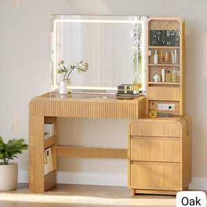May include: A light oak vanity with a large, illuminated mirror. The vanity features a built-in shelf for cosmetics and jewelry, along with three drawers. A small vase of flowers sits on the vanity top. The word "Oak" is in the bottom right corner.