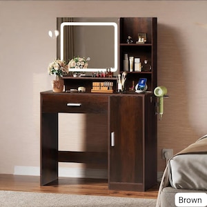 May include: A brown vanity with a lighted mirror, a drawer, and a cabinet. The vanity has shelves for storage and a small shelf for a hair dryer. The mirror is square with a white light border. The vanity is in a bedroom.