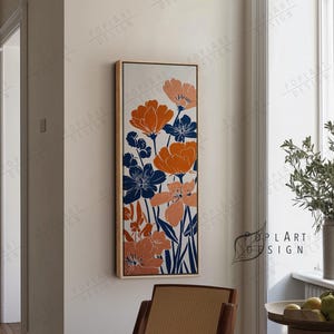 Op de afbeelding: Een rechthoekige ingelijste bloemenkunstprint. Het kunstwerk toont gestileerde oranje, marineblauwe en perzikroze bloemen tegen een witte achtergrond. De lijst is licht van kleur. De woorden "POPLART DESIGN" zijn zichtbaar in de afbeelding.