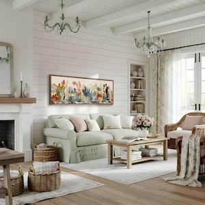 May include: A cozy living room scene with a light green sofa, floral artwork, and a wooden coffee table. Wicker baskets and a patterned rug add texture. Two crystal chandeliers hang from the white ceiling, creating a warm and inviting atmosphere.