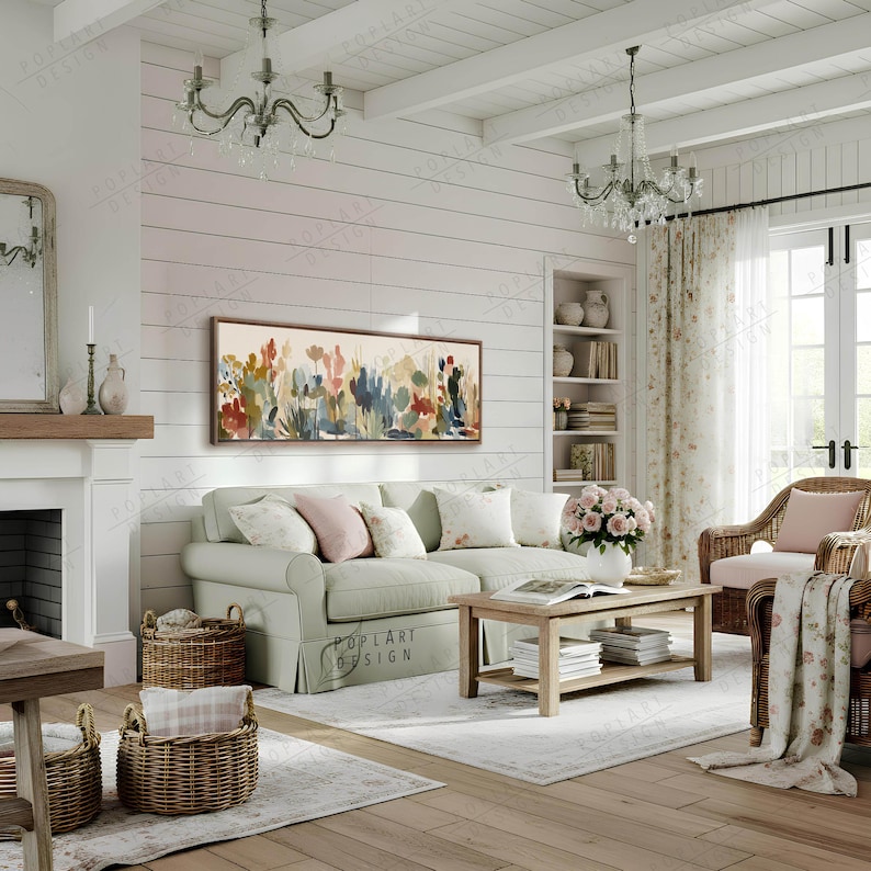 May include: A cozy living room scene with a light green sofa, floral artwork, and a wooden coffee table. Wicker baskets and a patterned rug add texture. Two crystal chandeliers hang from the white ceiling, creating a warm and inviting atmosphere.