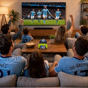 May include: A bright lime green video game controller stand featuring a circular Manchester City Football Club logo on the front, positioned on a wooden coffee table in front of a large television screen displaying a professional soccer match.